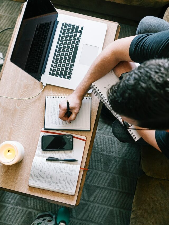 man in black t-shirt sitting at the table using macbook pro