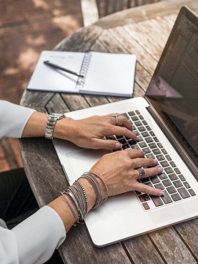person typing on MacBook Pro on brown wooden table during daytime photo