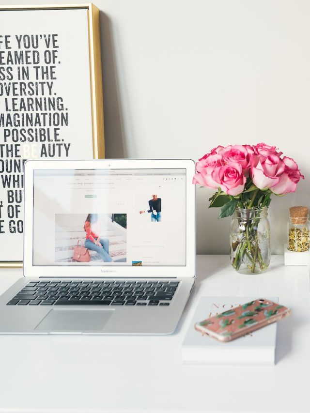 MacBook Air beside gold-colored study lamp and spiral books