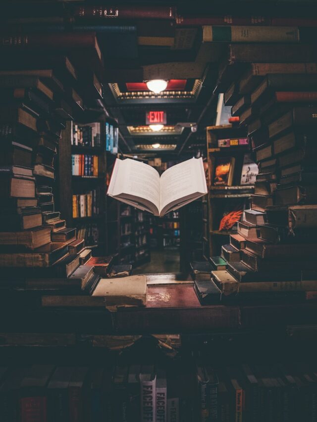 view of floating open book from stacked books in library