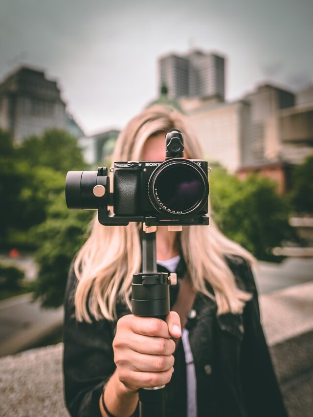 selective focus photography of woman holding camera gimbal