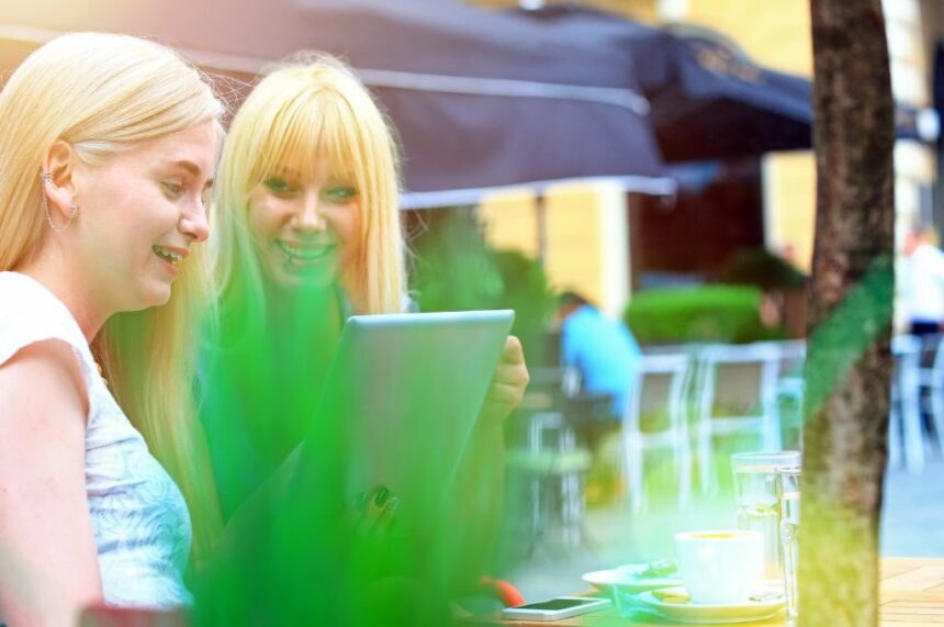 Girls interacting on tablet in coffee shop