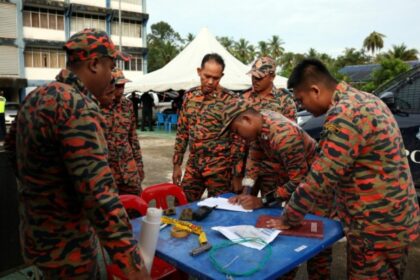 Members of the Fire and rescue department take part in the search and rescue operation at the Air Putih police station in Chukai
