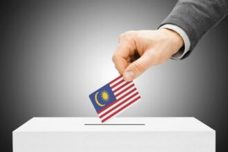 man inserting flag into ballot box