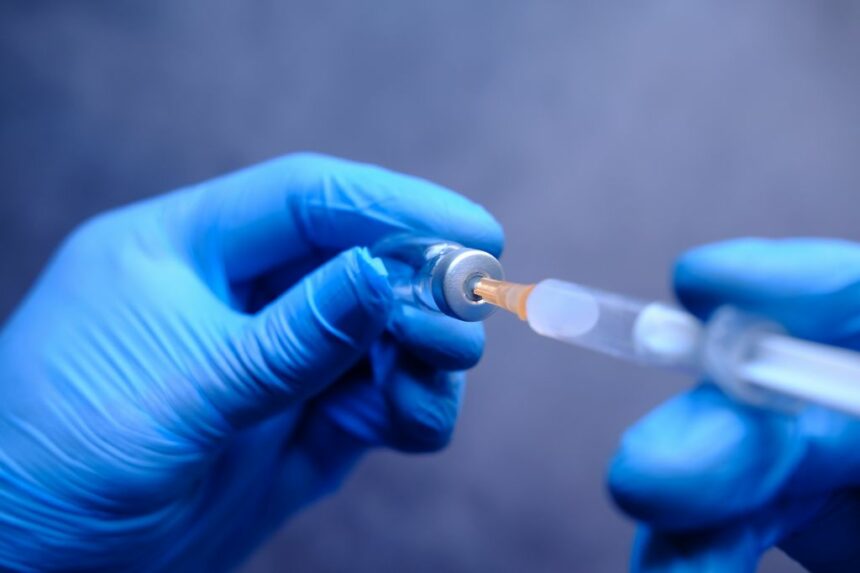 Doctor hands in medical gloves holds syringe and vaccine