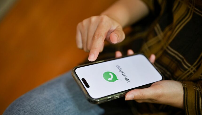 female hands holding a smartphone white whatsapp logo on screen