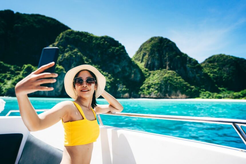 Travel influencer at the sea using phone for selfie