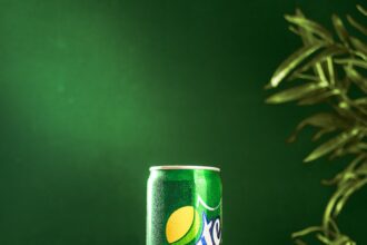 a can of sprite on a wooden stand with limes