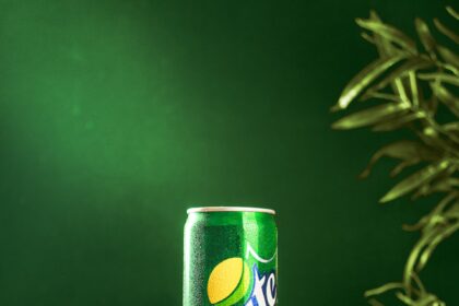 a can of sprite on a wooden stand with limes
